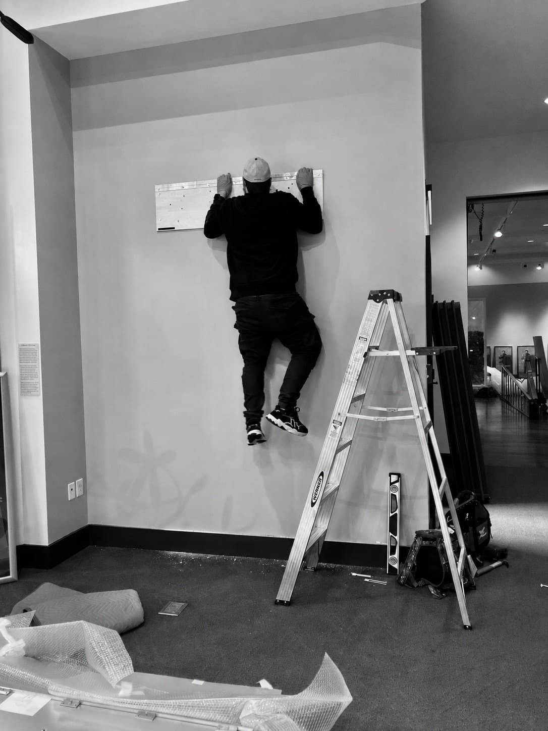Installer aligning wall-mounted hardware in a gallery space