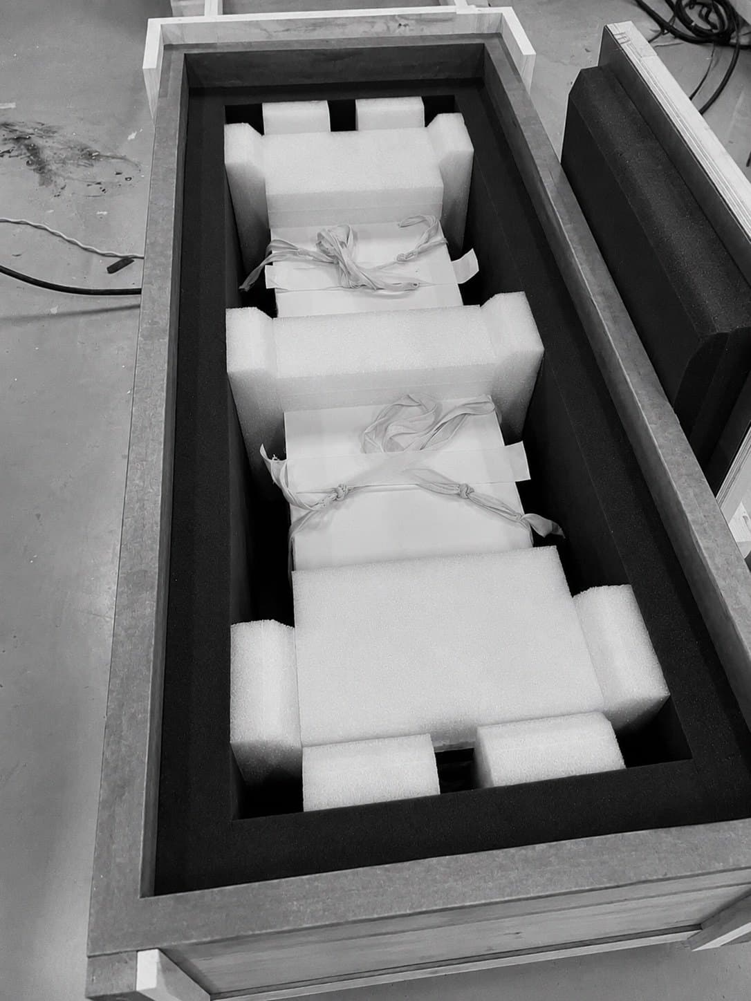 Foam-lined protective crate holding wrapped objects